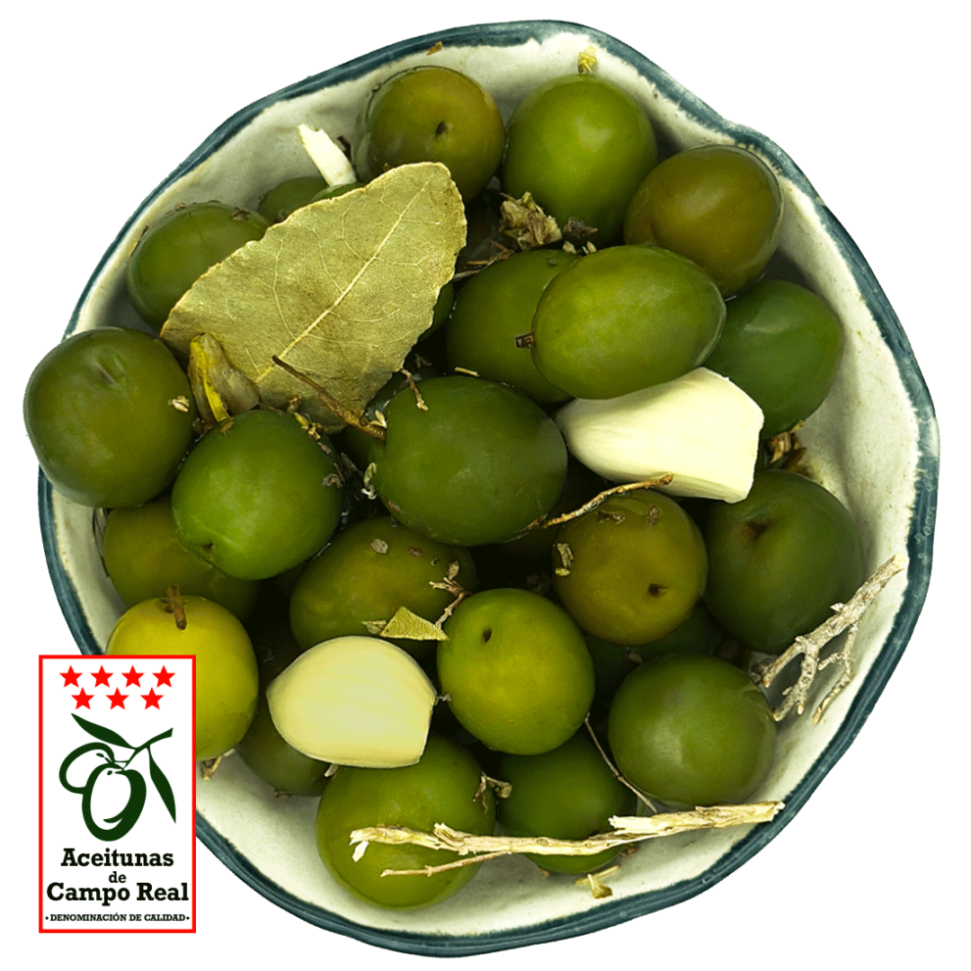 Primer plano de aceitunas verdes de Campo Real con aliño de especias mediterráneas em un cuenco blanco.