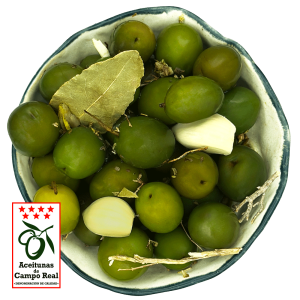 Primer plano de aceitunas verdes de Campo Real con aliño de especias mediterráneas em un cuenco blanco.