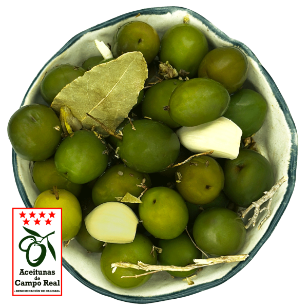 Primer plano de aceitunas verdes de Campo Real con aliño de especias mediterráneas em un cuenco blanco.